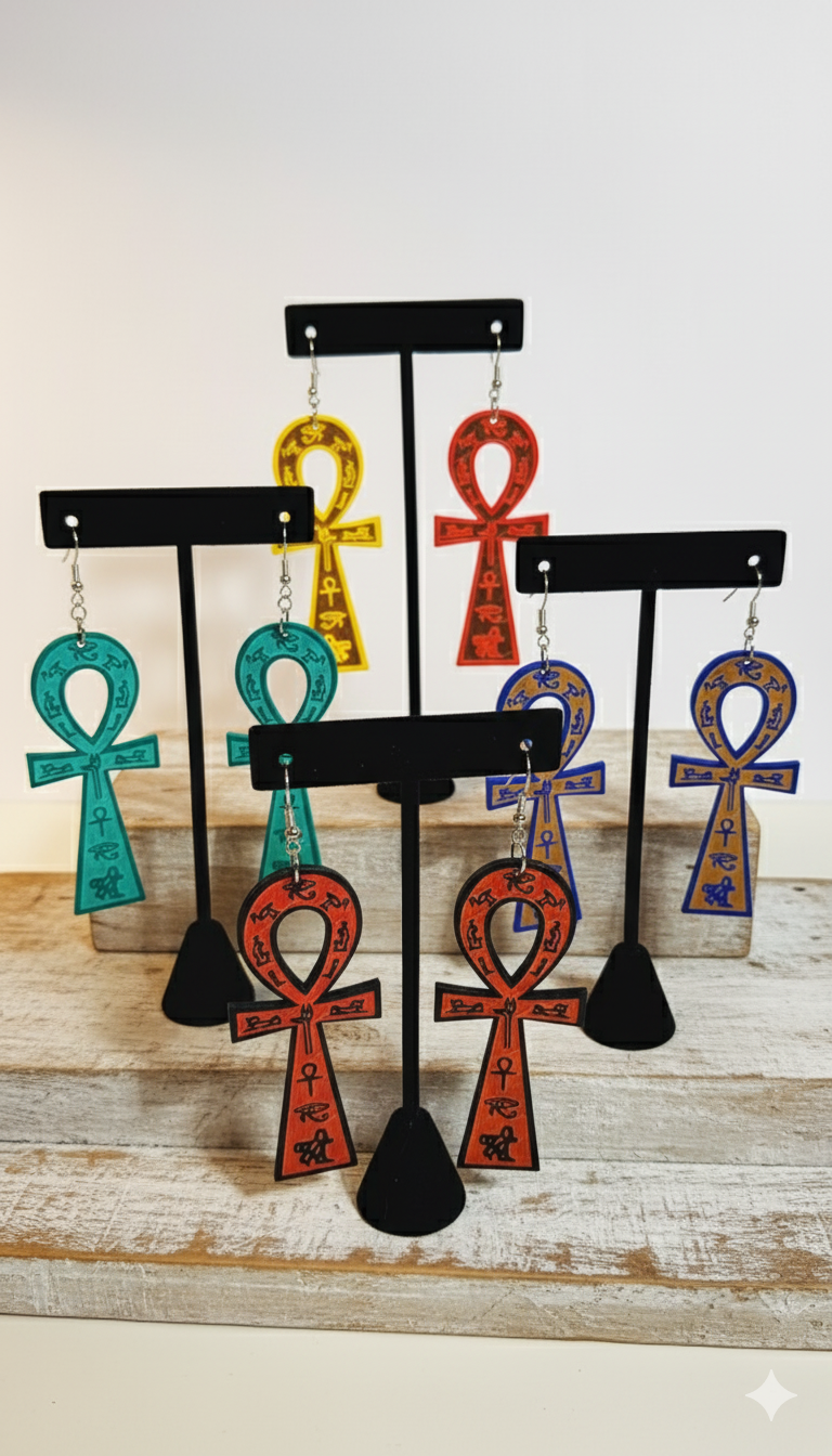Ankh-shaped earrings on black stands against a white background