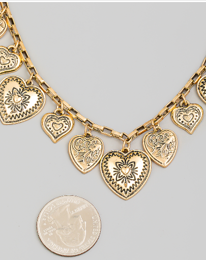 Gold heart-shaped charm bracelet on a light gray background