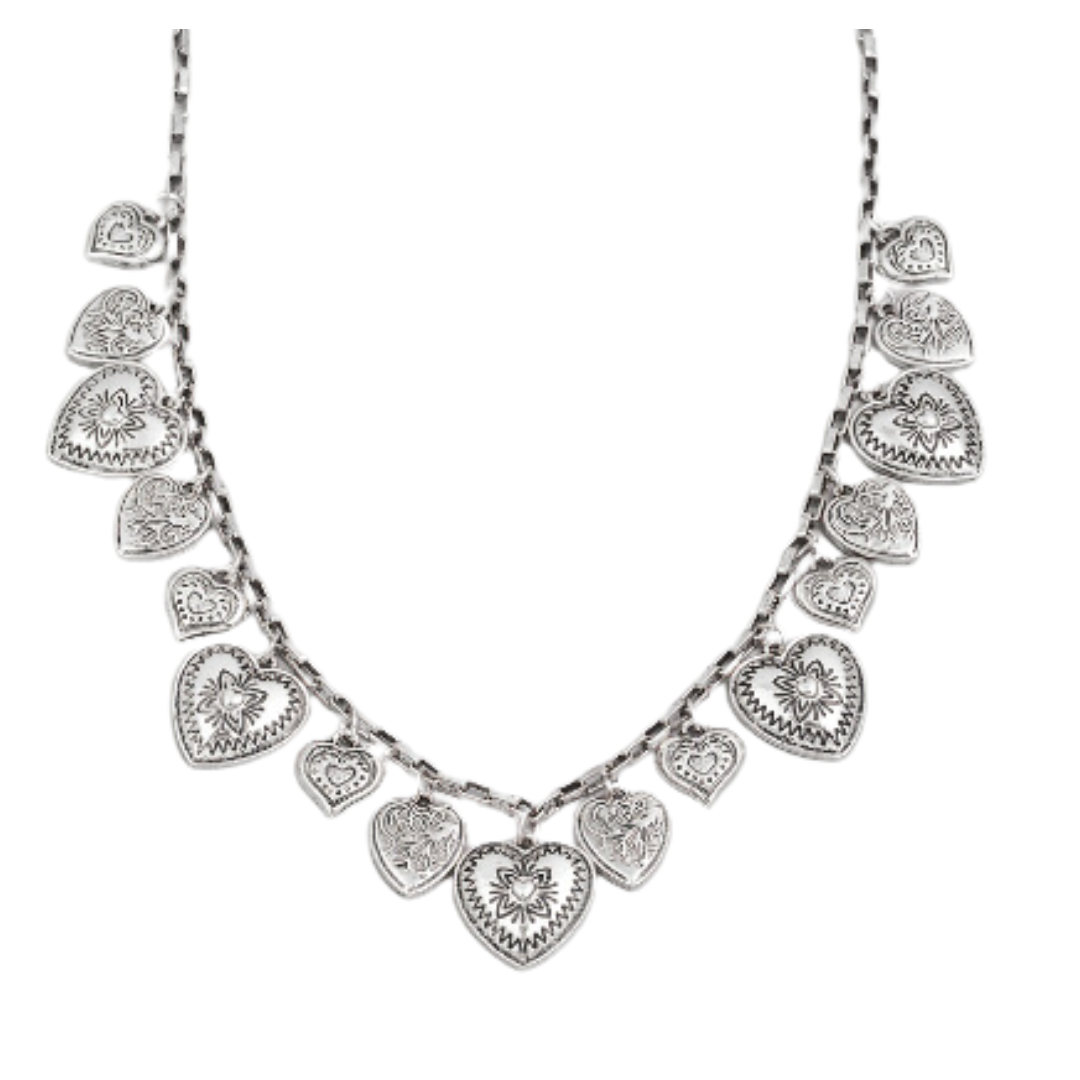 necklace and earrings on a white surface with a pink rose and lit candle in the background.