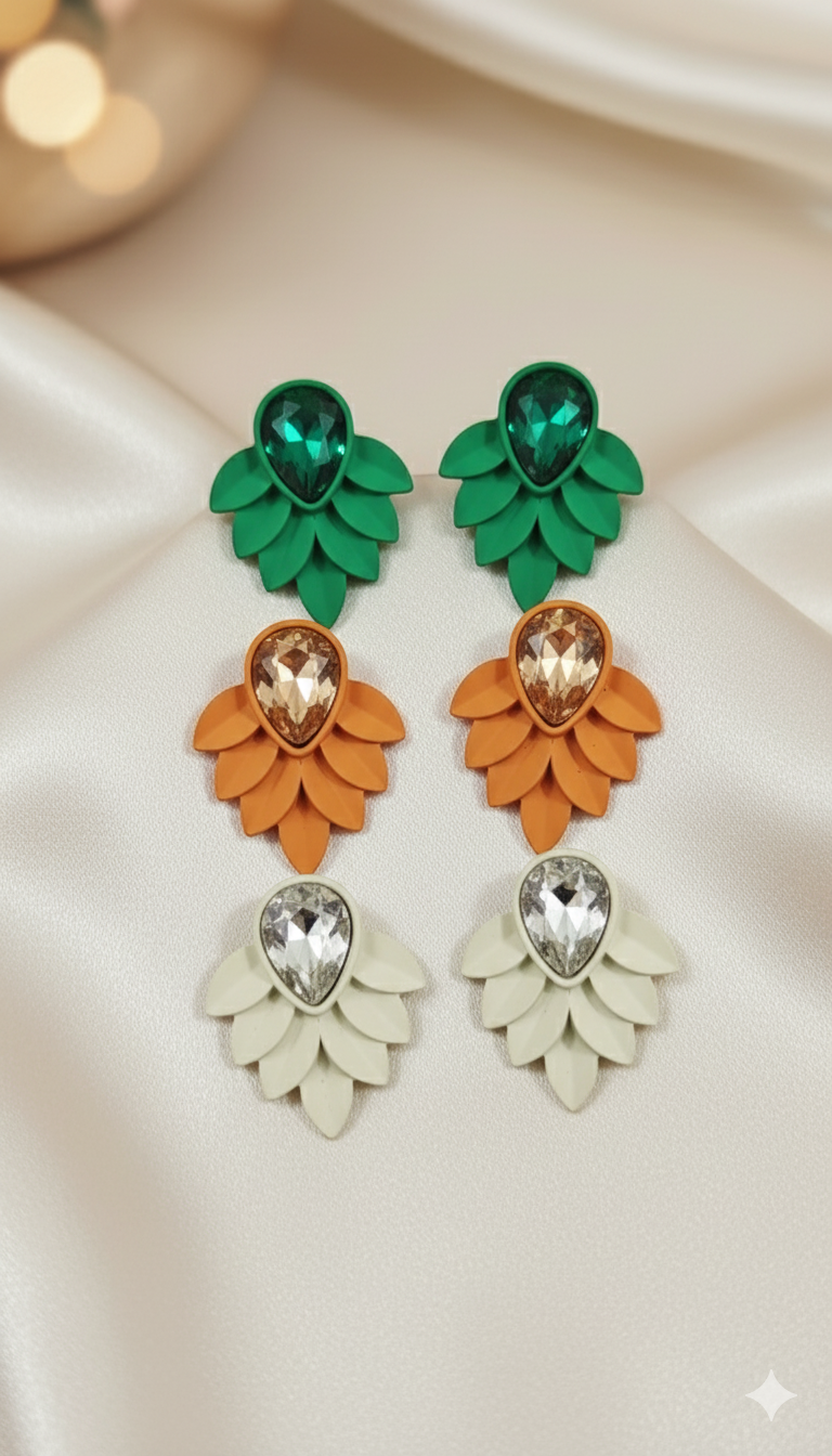 Pair of earrings with green, orange, and white leaves on a beige background