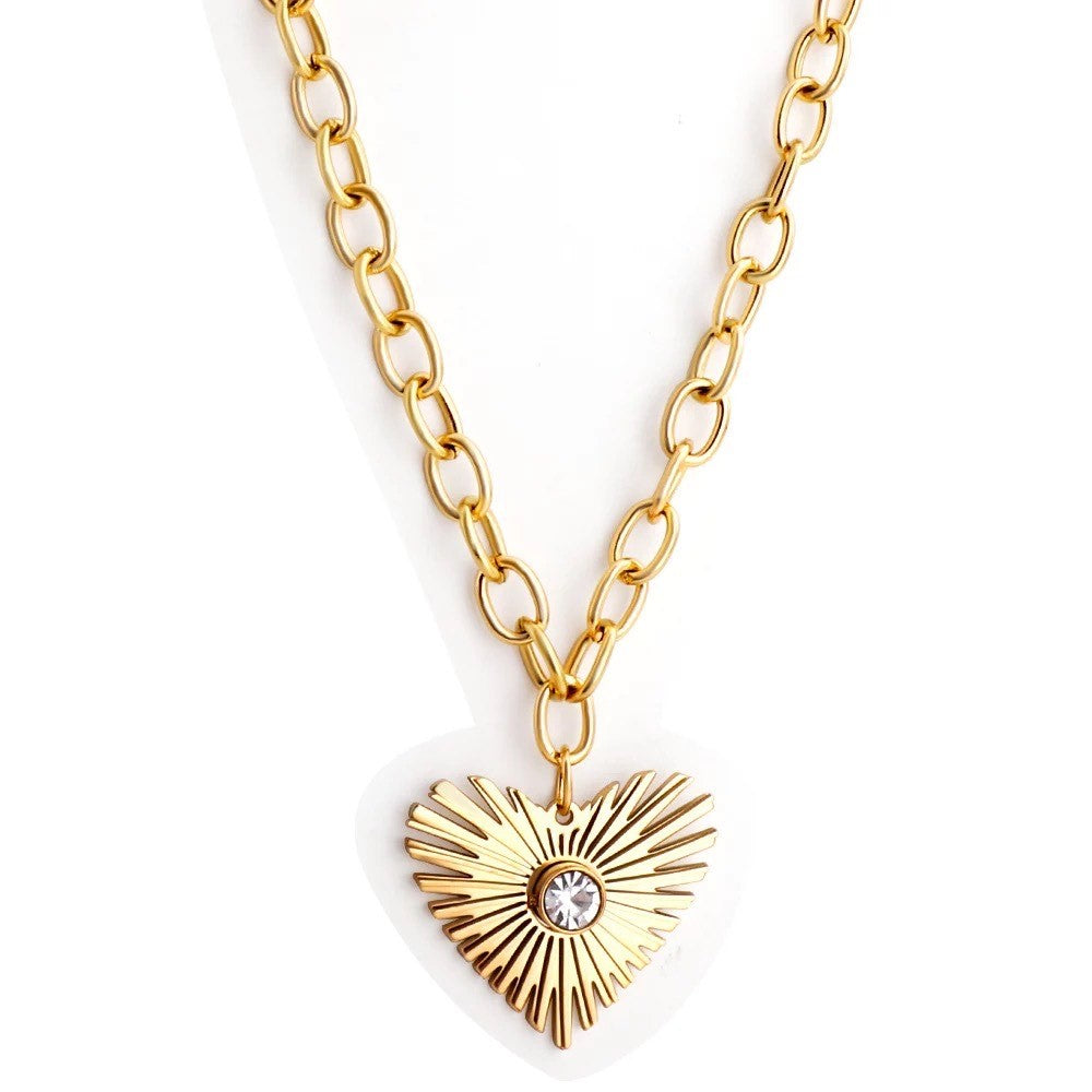 A gold-colored necklace with a heart-shaped pendant featuring a central diamond, attached to a gold chain.